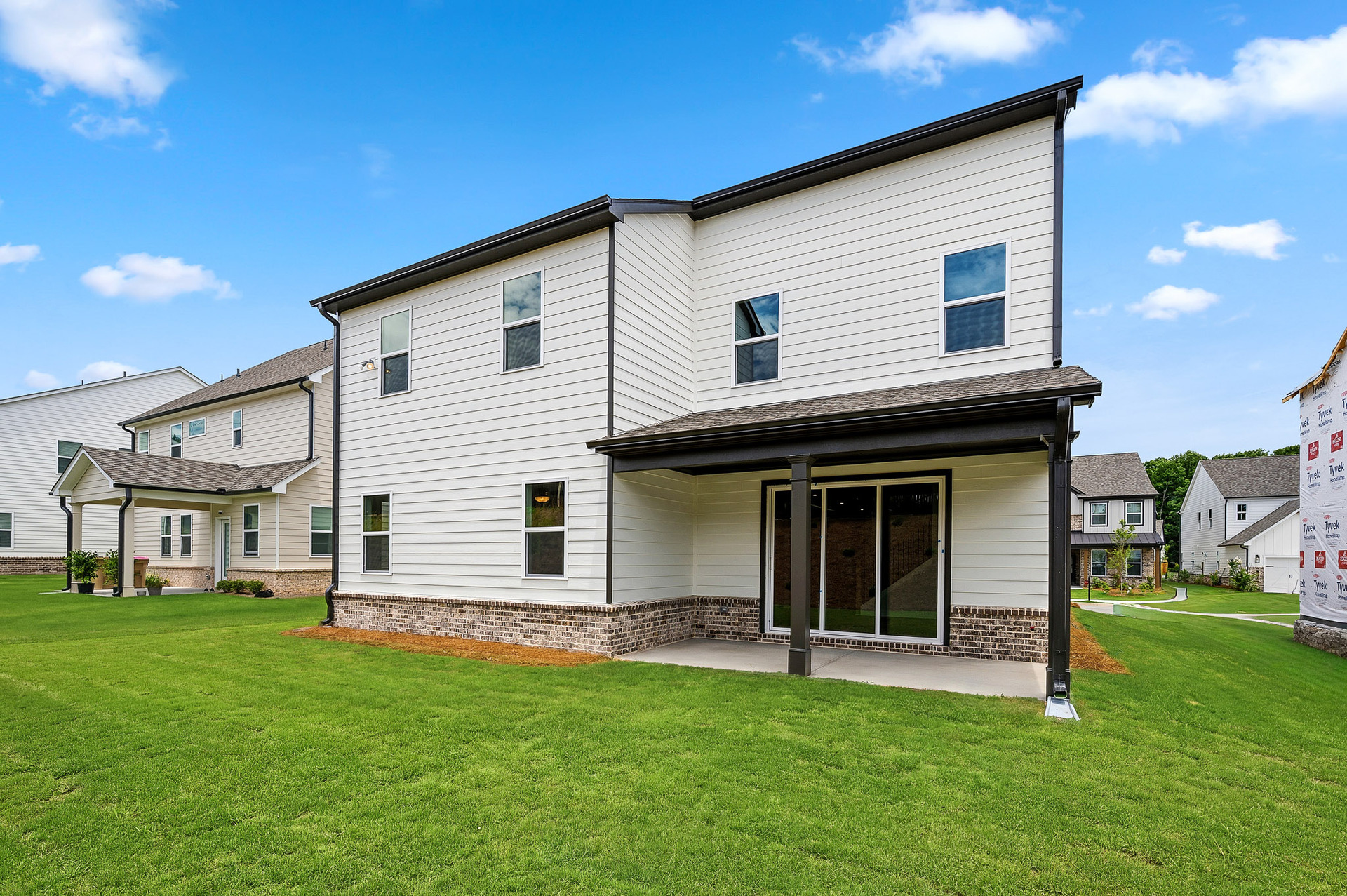 back of 2-story home with covered patio and landscaping