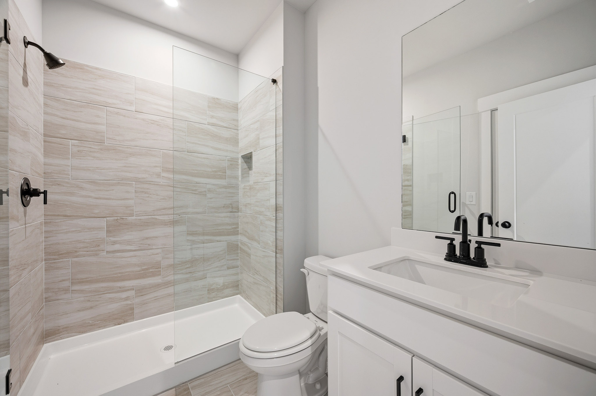 secondary bathroom with white cabinets and tile flooring