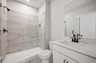 secondary bathroom with white cabinets and tile flooring