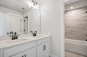 secondary bathroom with white cabinets and tile flooring