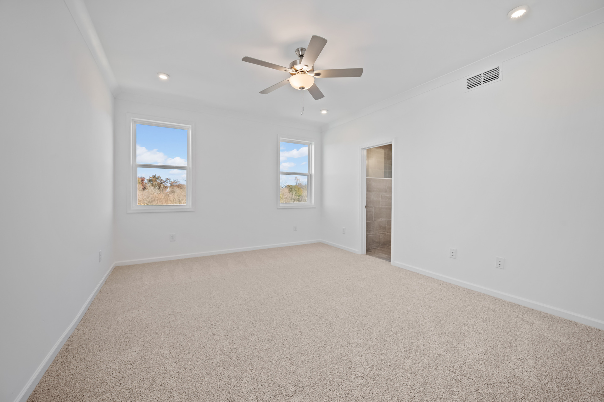 primary bedroom with windows and carpet