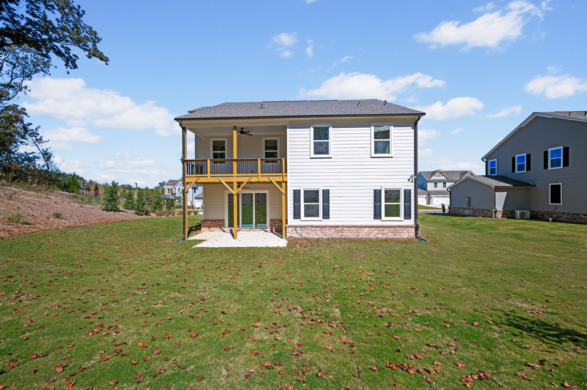 back of 2-story home with covered patio and deck off of primary bedroom