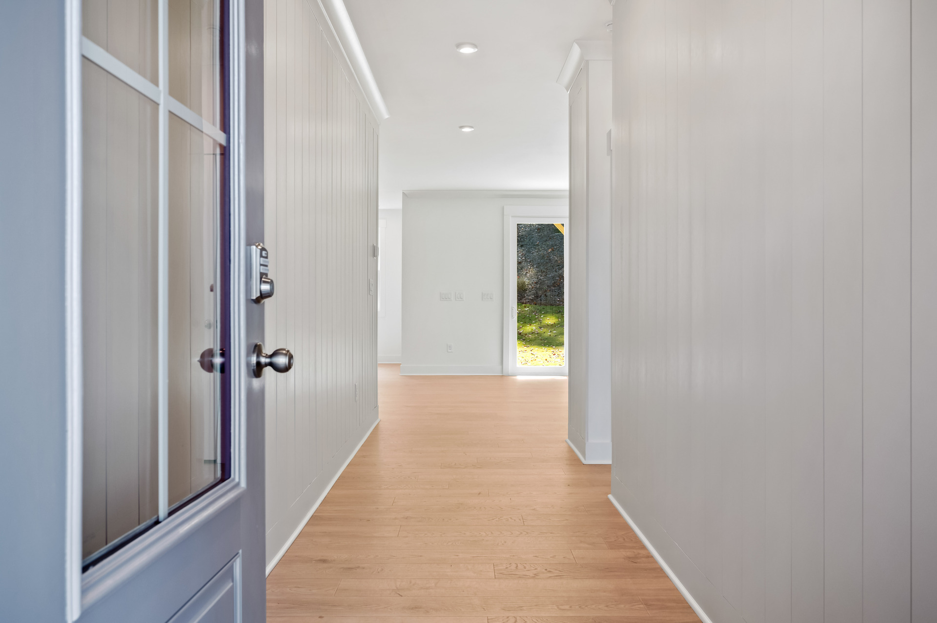 foyer with shiplap detail on the walls and a glass pane front door