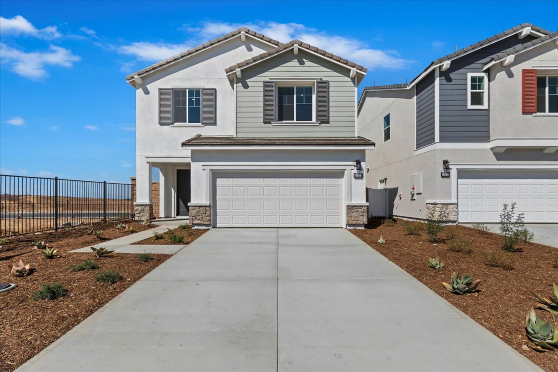 two-story exterior with a white windowless garage and a beige brick trim