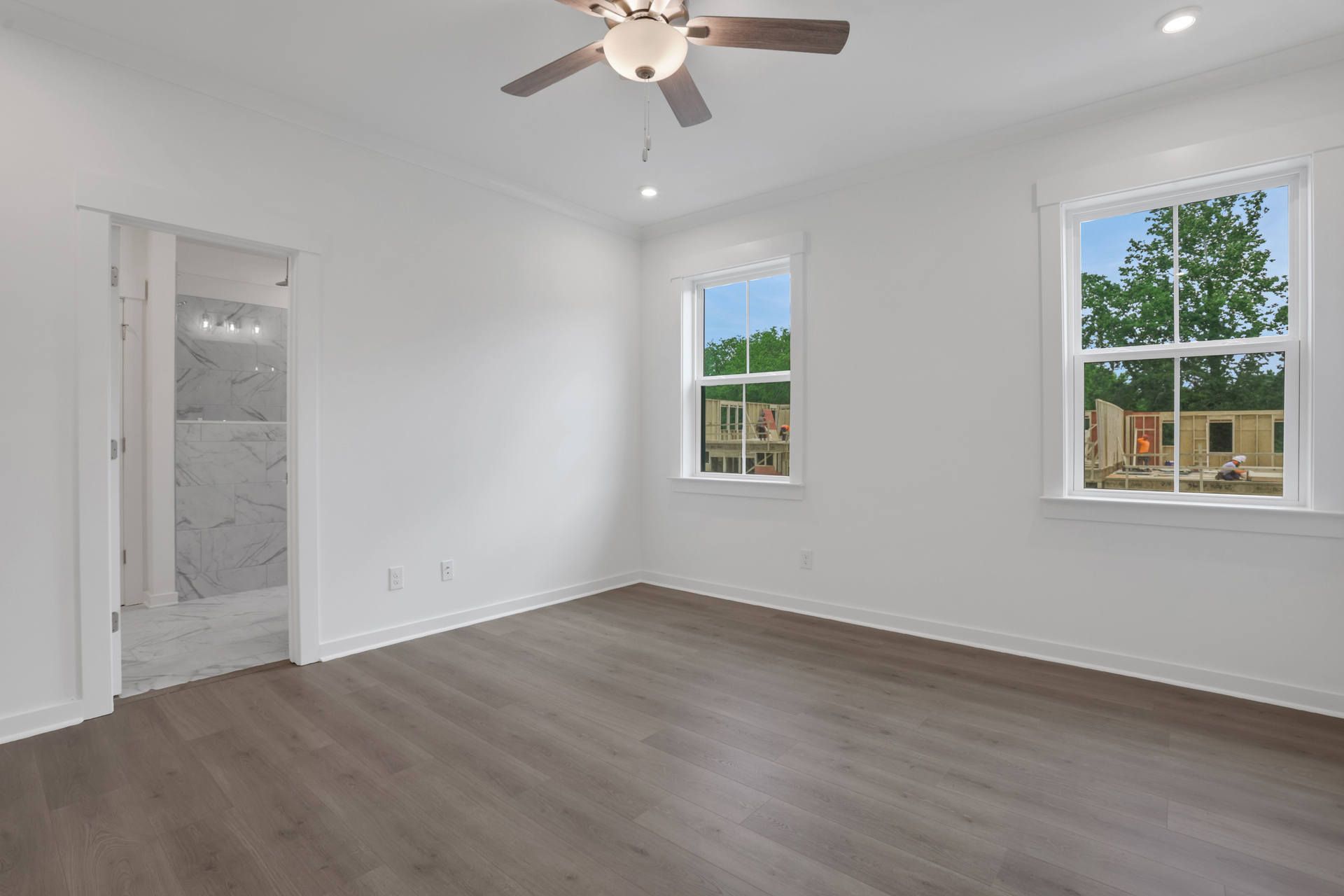 primary bedroom with windows and hard surface floors