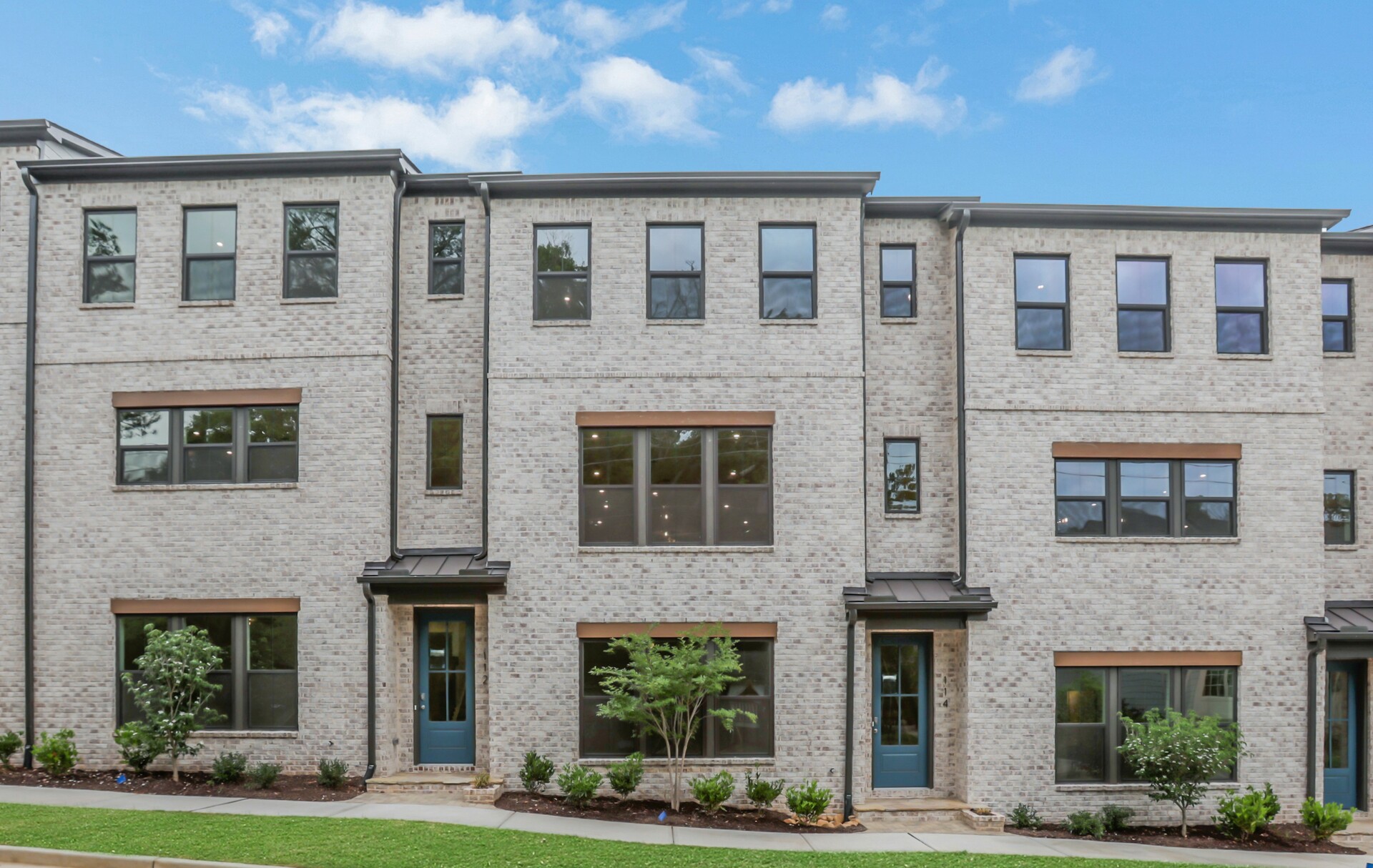 front of 3-story townhome with light brick and wood accents