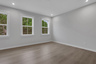 primary bedroom with windows and hard surface floors