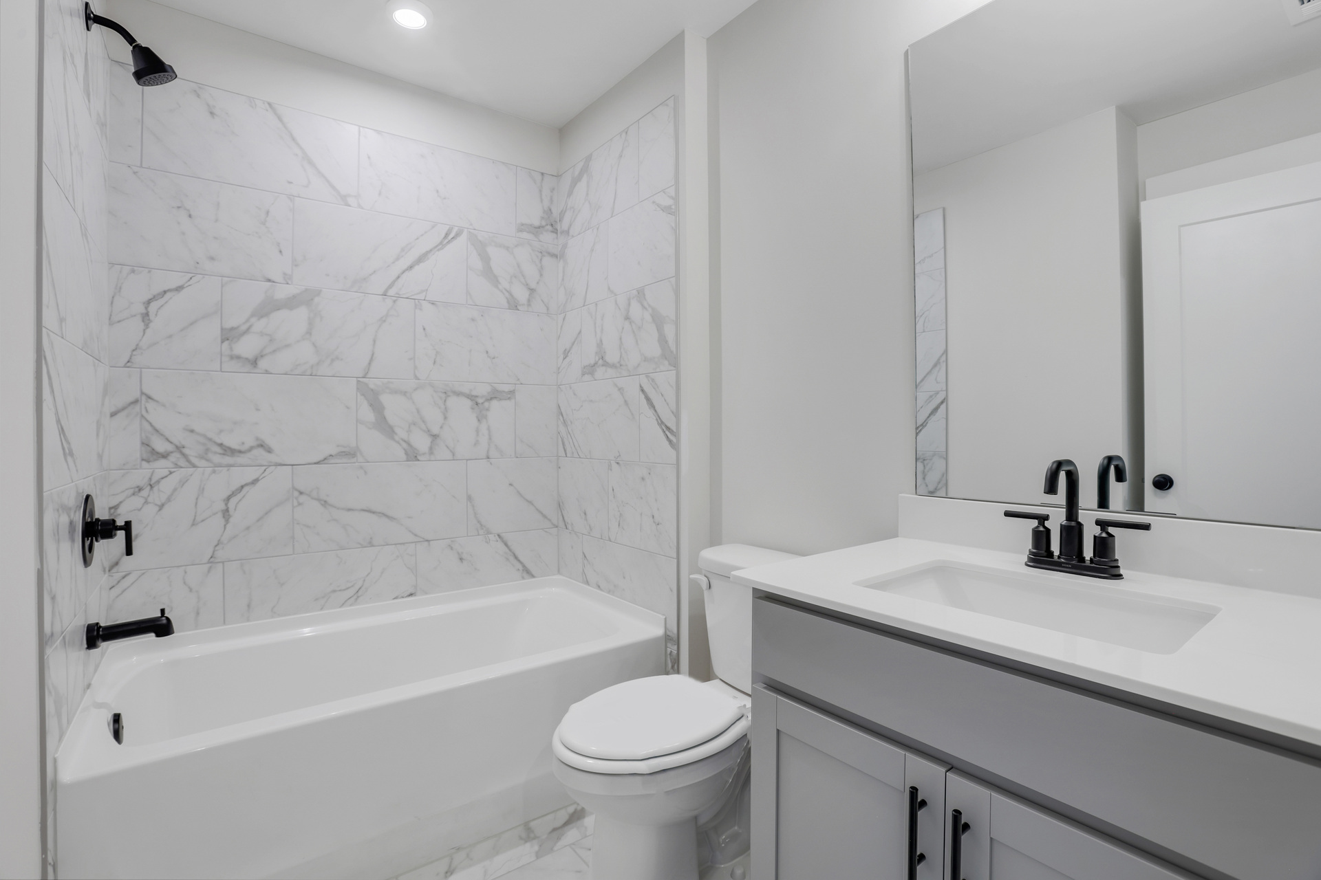 secondary bathroom with gray cabinets and tile flooring