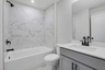 secondary bathroom with gray cabinets and tile flooring
