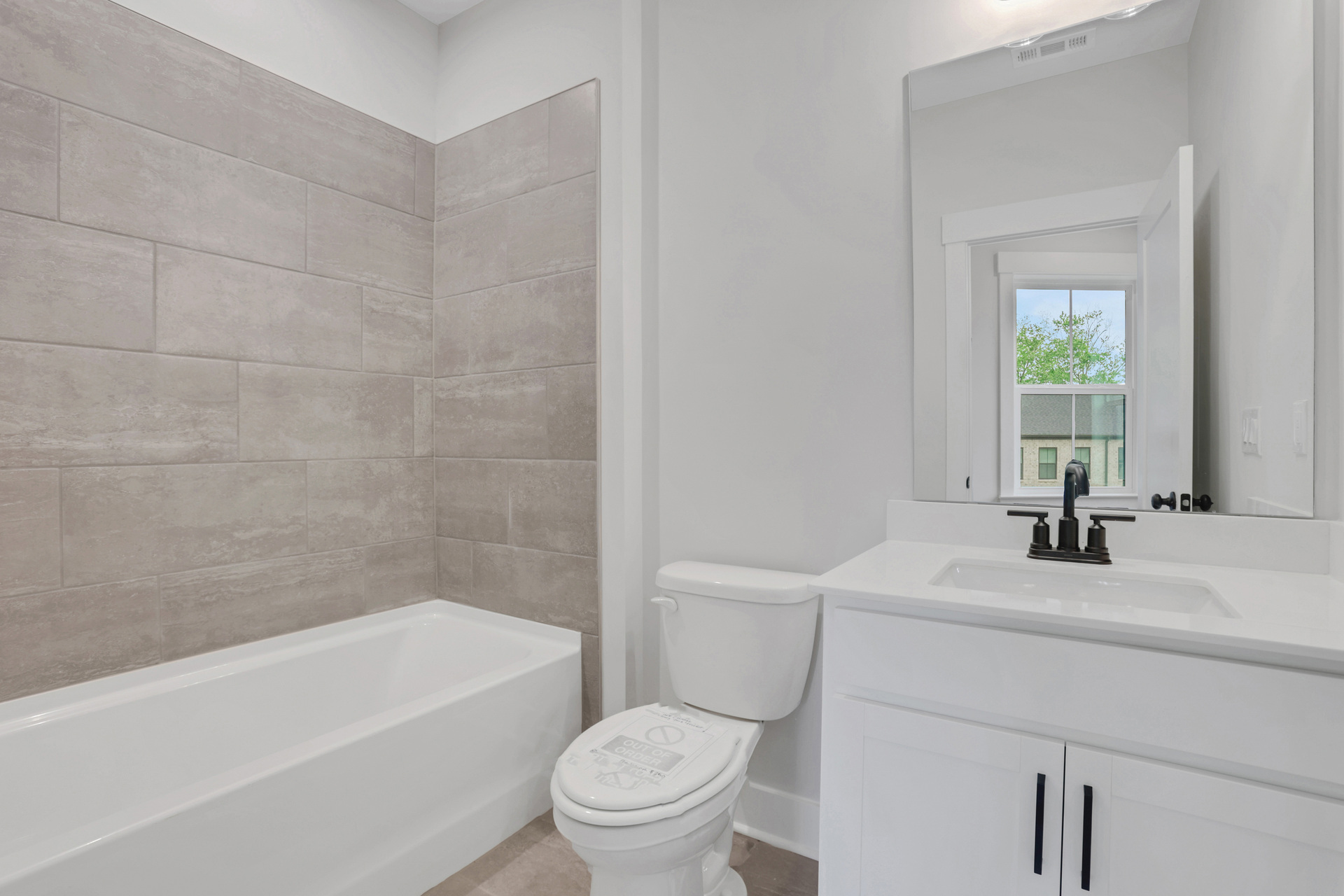 secondary bathroom with white cabinets and tile flooring