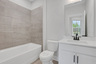 secondary bathroom with white cabinets and tile flooring