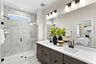 bathroom with frameless shower and two sinks