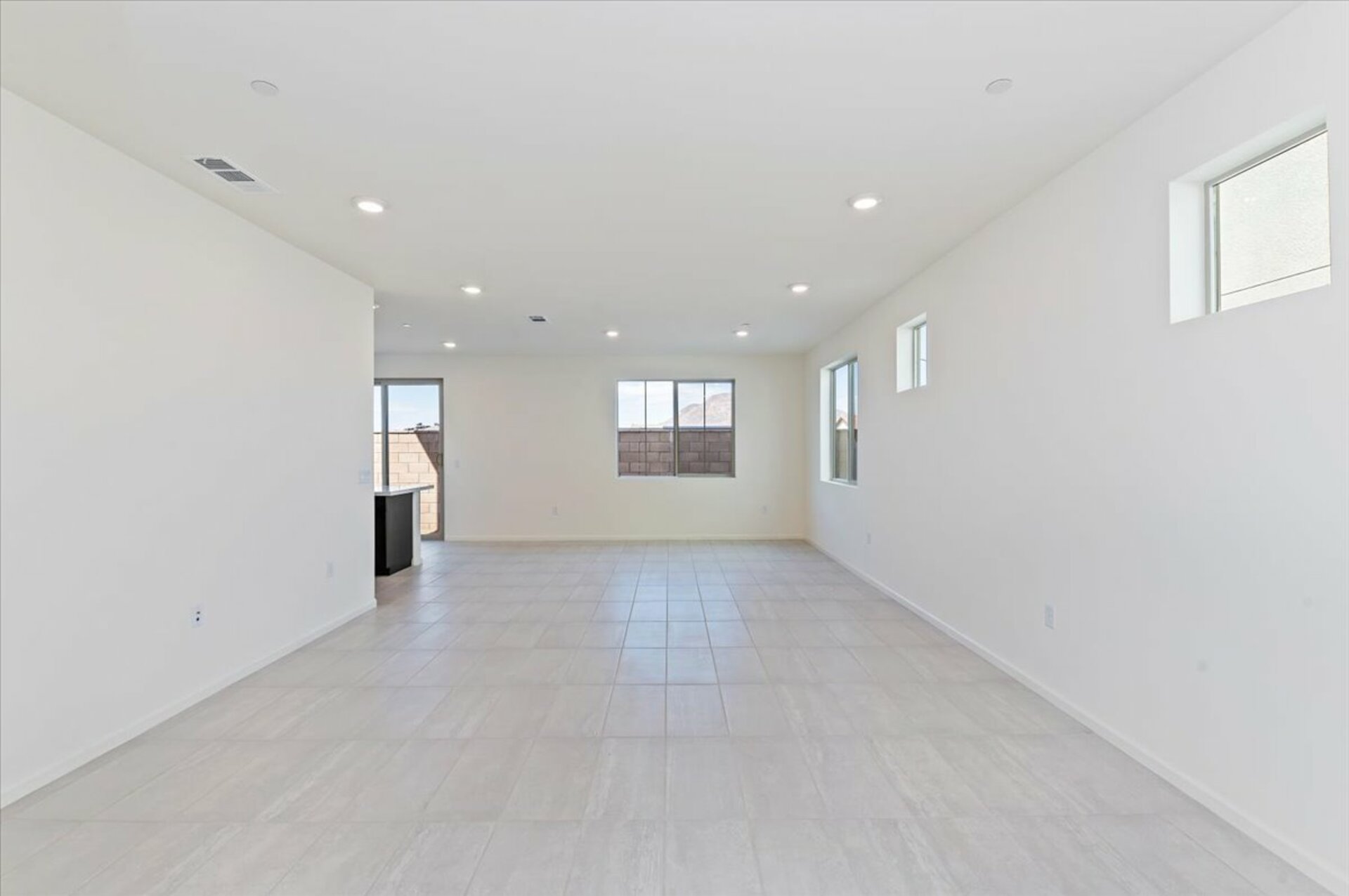 great room with white tiled floor and windows along the wall