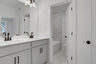 secondary bathroom with gray cabinets and tile flooring