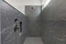 primary bathroom with large walk-in shower featuring dark tile