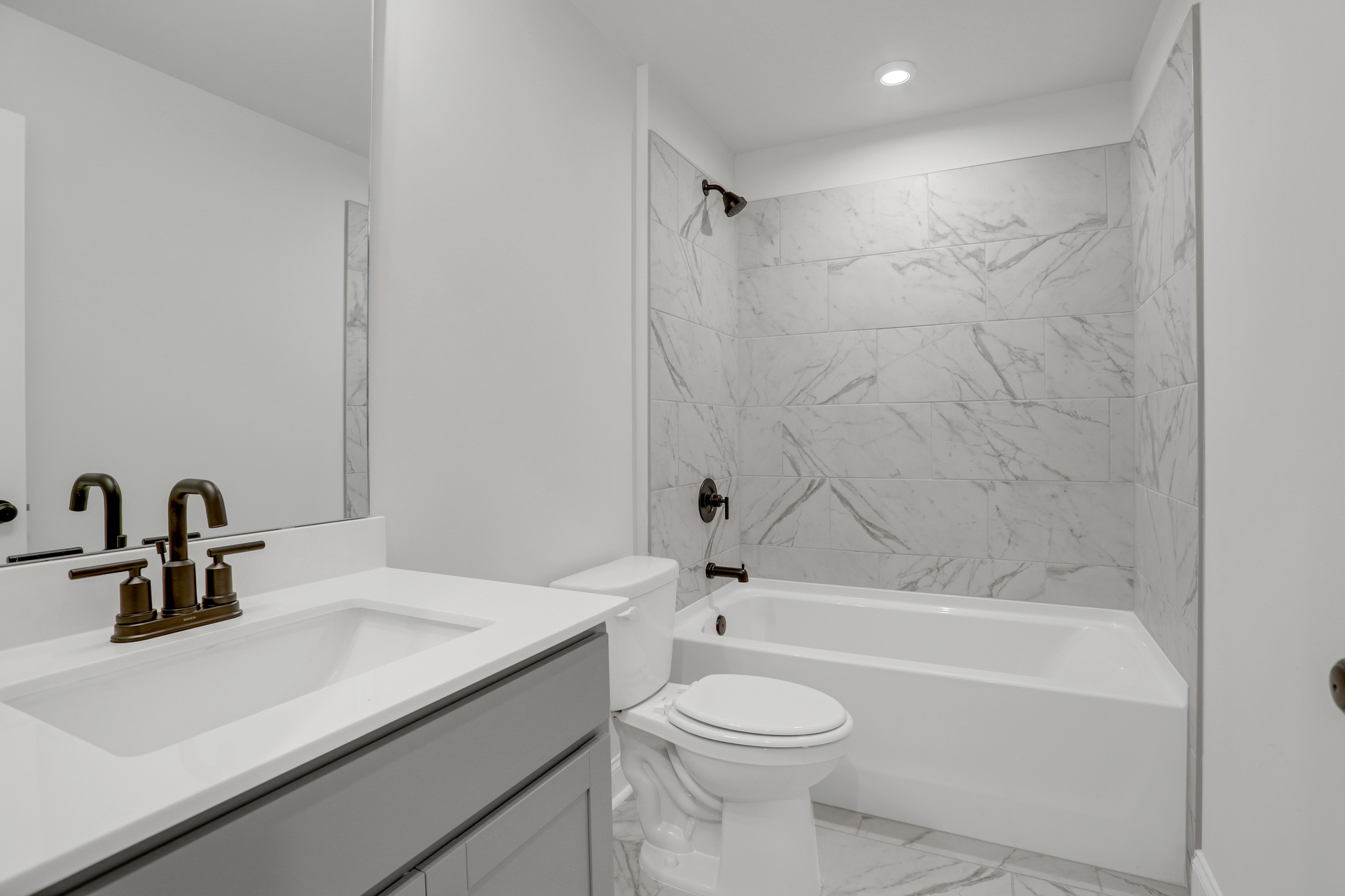 secondary bathroom with gray cabinets and tile flooring