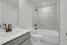 secondary bathroom with gray cabinets and tile flooring