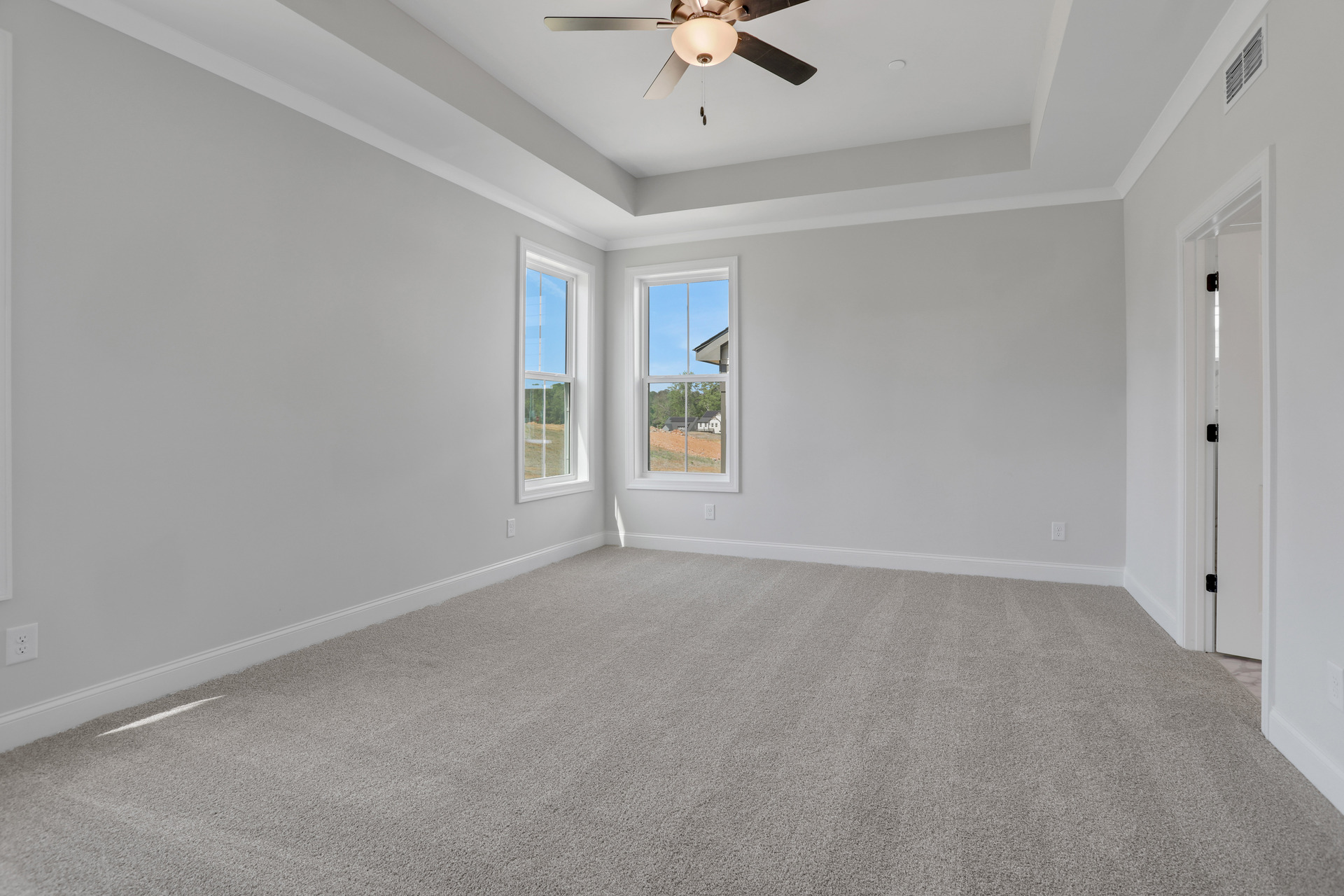 primary bedroom with windows and carpet
