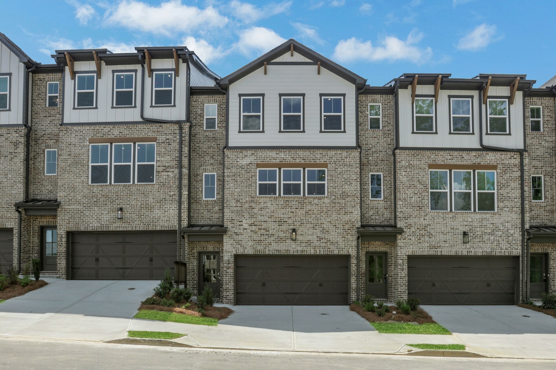 front of 3-story townhome with dark brick and accents and light siding