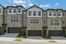 front of 3-story townhome with dark brick and accents and light siding