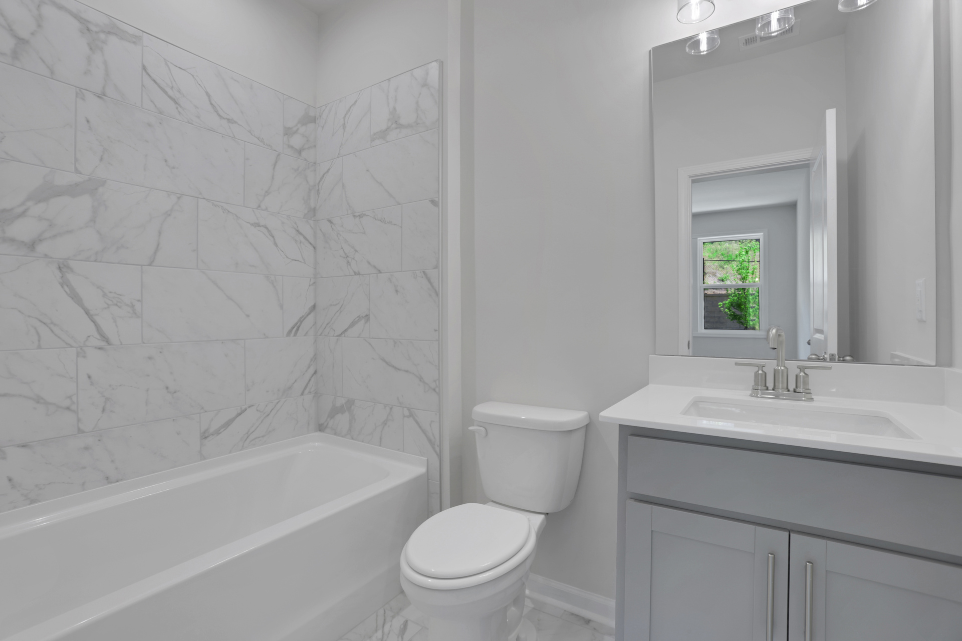 secondary bathroom with gray cabinets and tile flooring