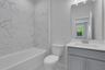 secondary bathroom with gray cabinets and tile flooring