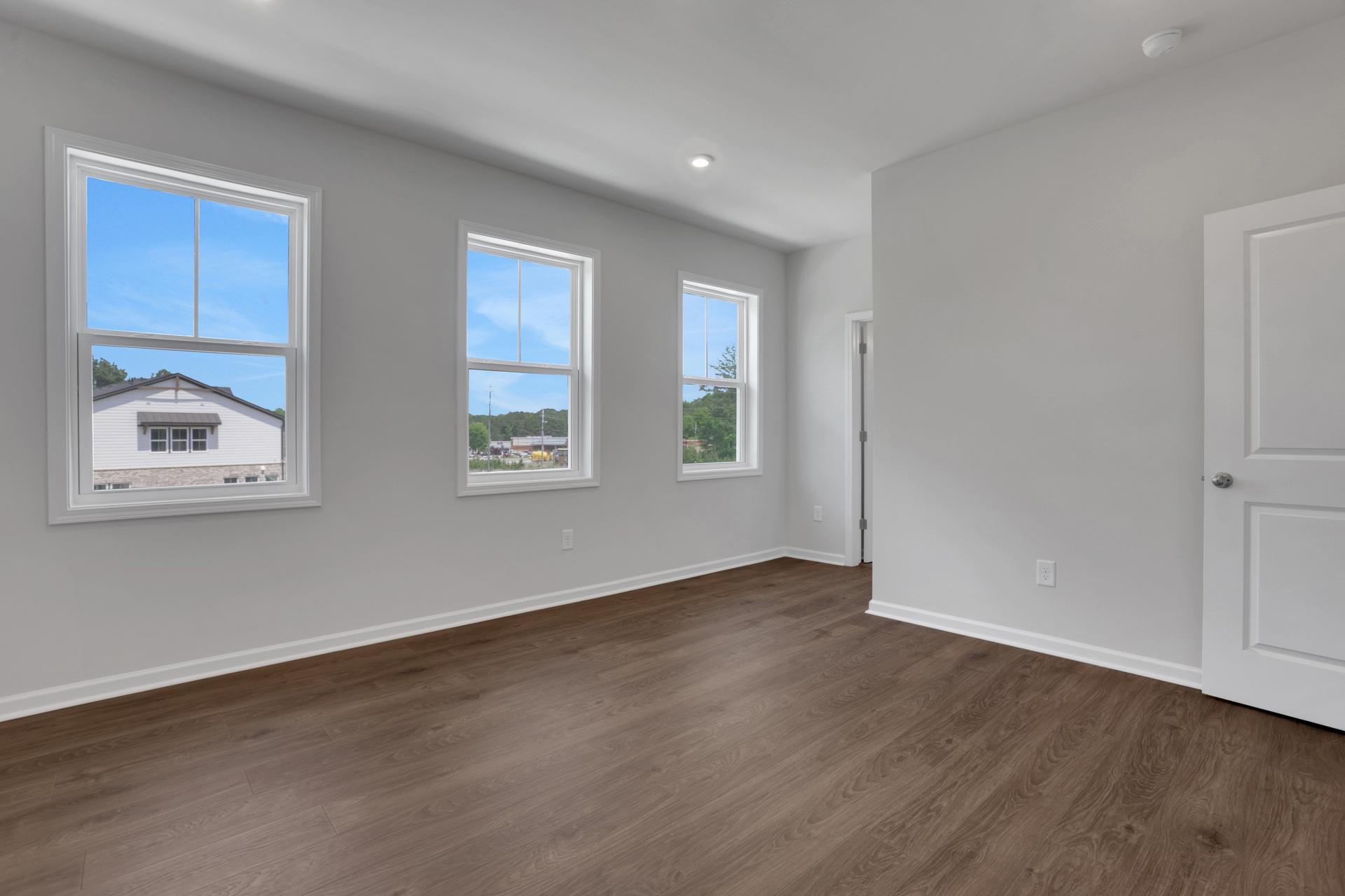 primary bedroom with windows and hard surface flooring 