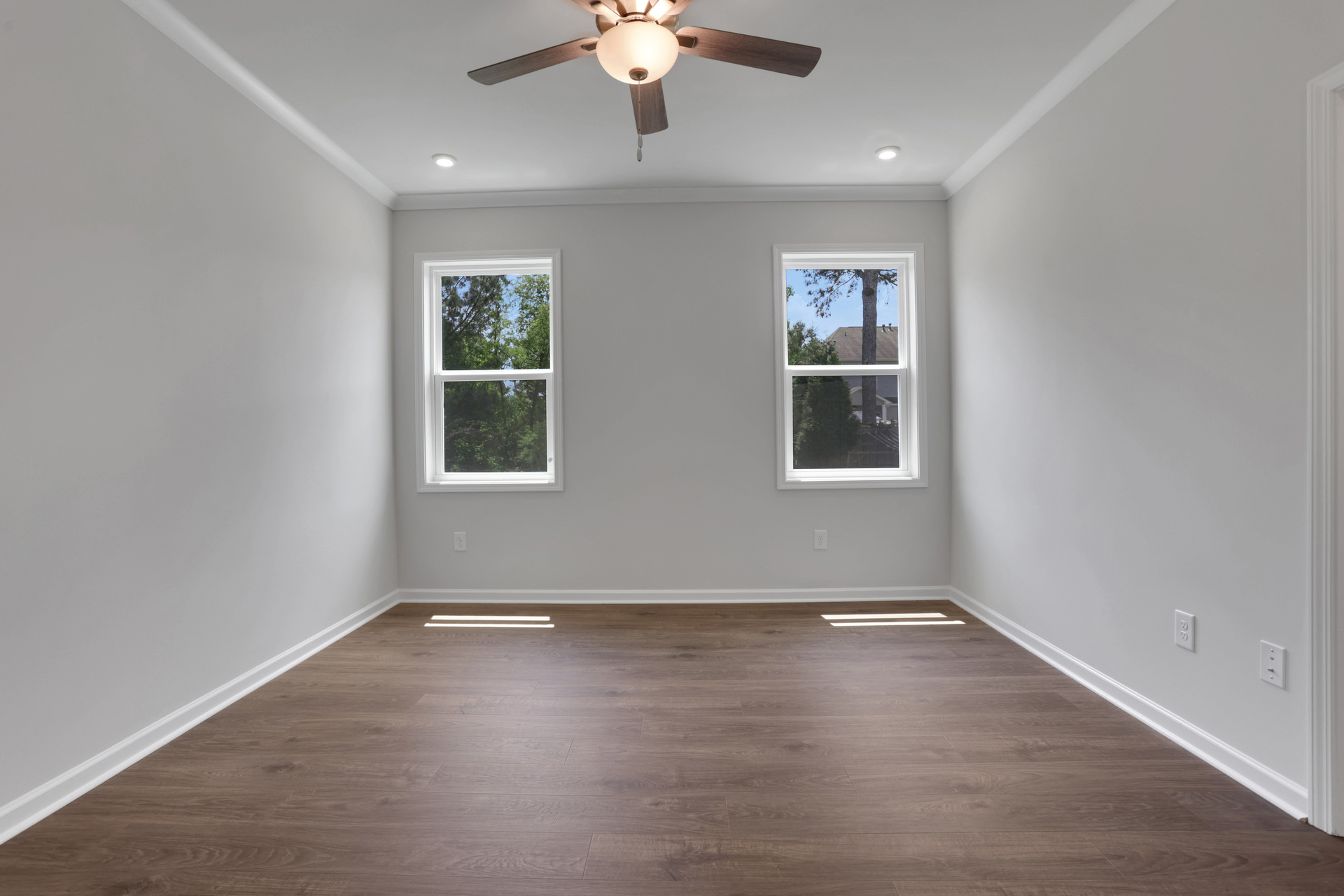 primary bedroom with windows and hard surface flooring 