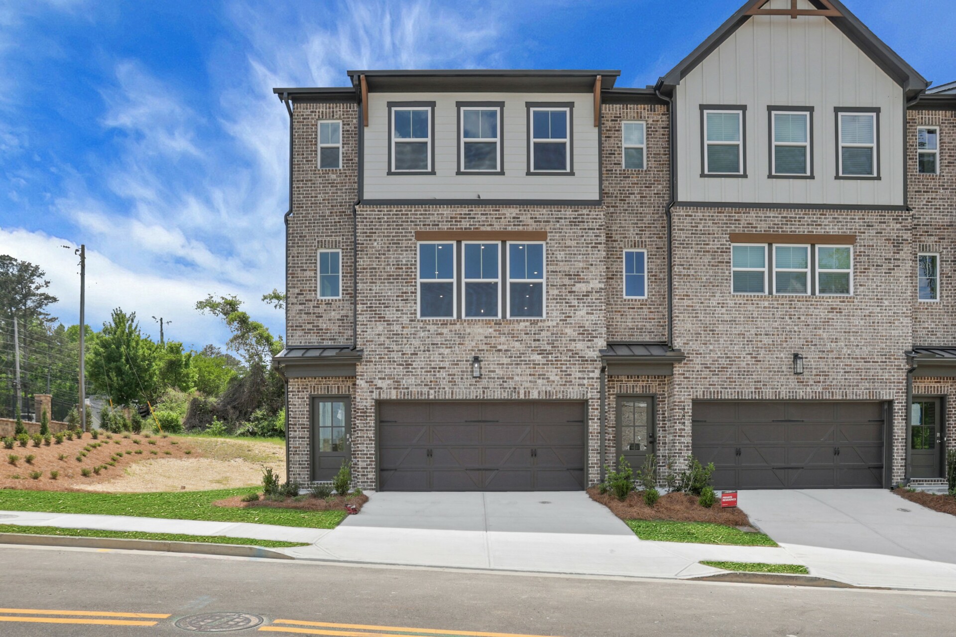front of 3-story townhome with dark brick and light siding 