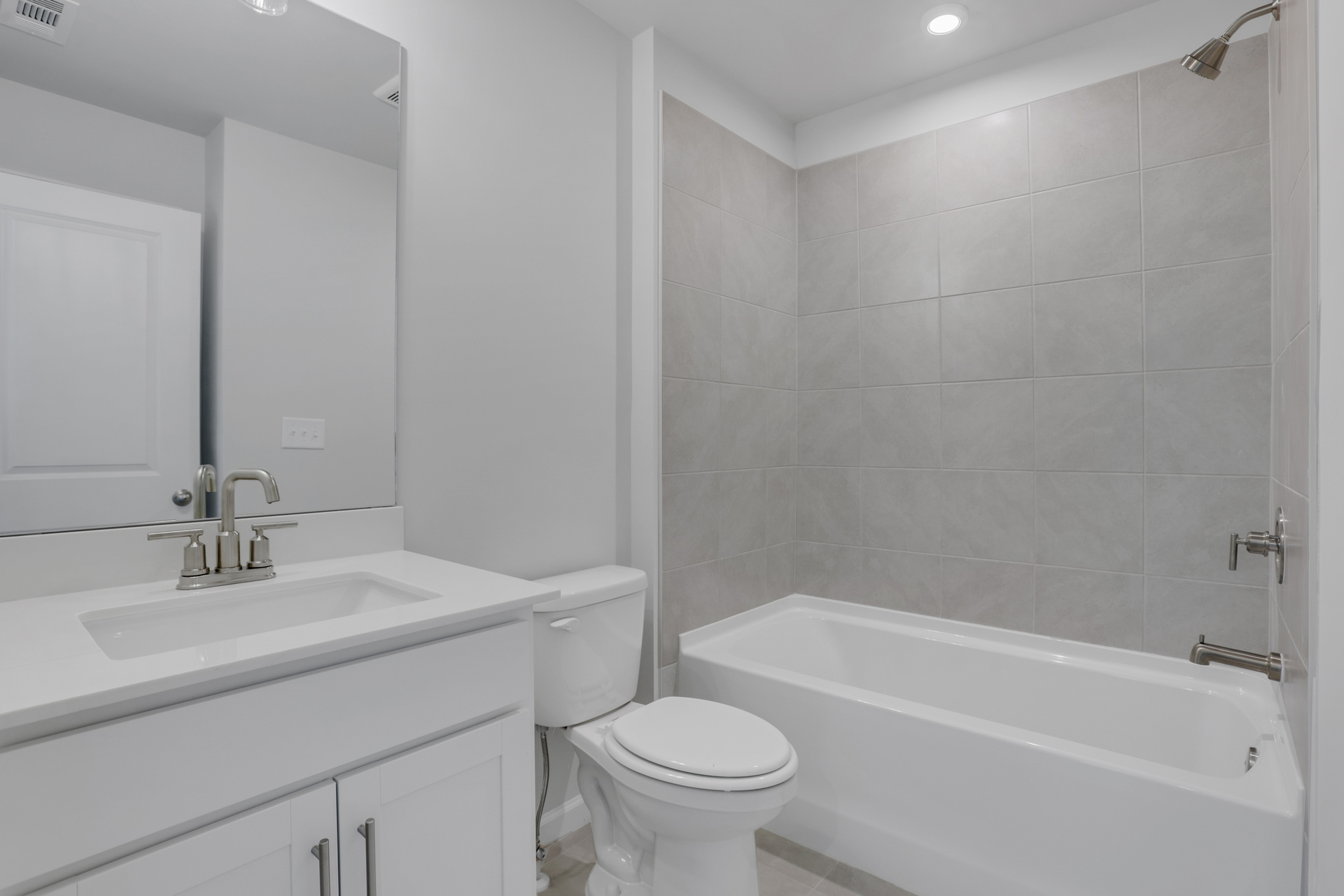 secondary bathroom with white cabinets and tile flooring