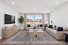 great room with two tans sofas, patterned tan & blue area rug, light wood coffee table, and multiple windows