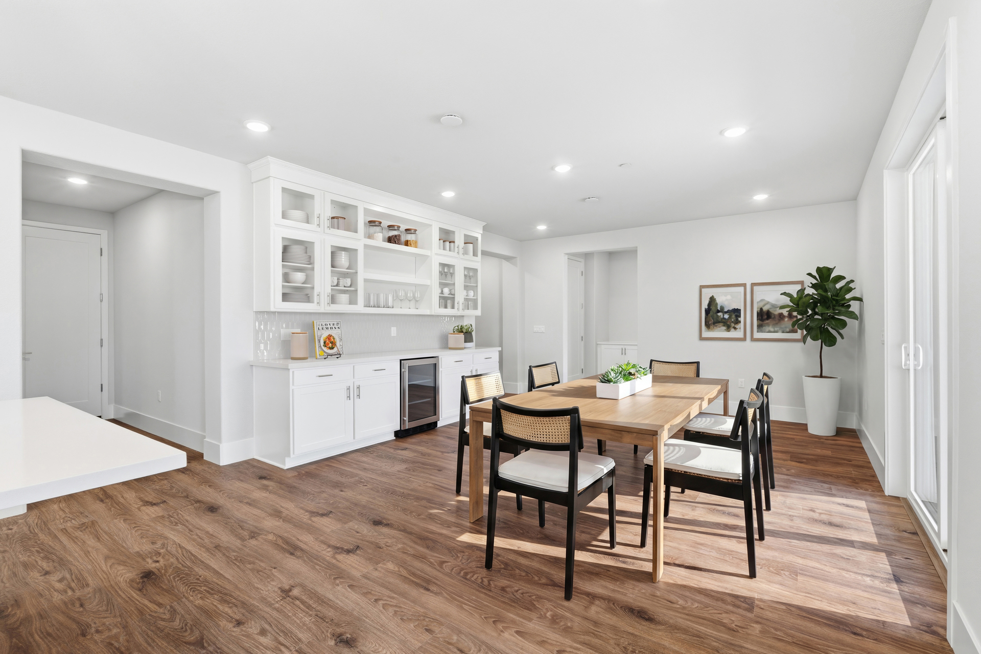 dining room with wood floors, white built-in cabinets with beverage refrigerator, wood table with six black chairs, and sliding glass door