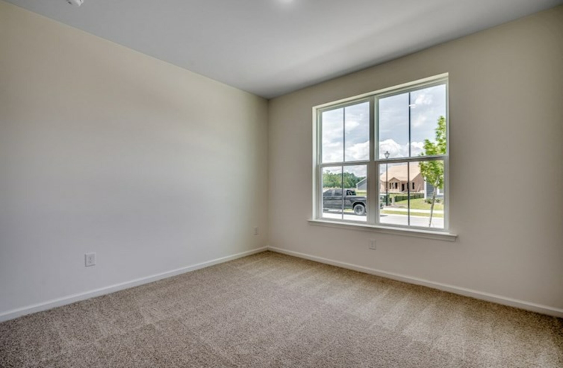 cozy room with tan walls, large window and carpeting throughout
