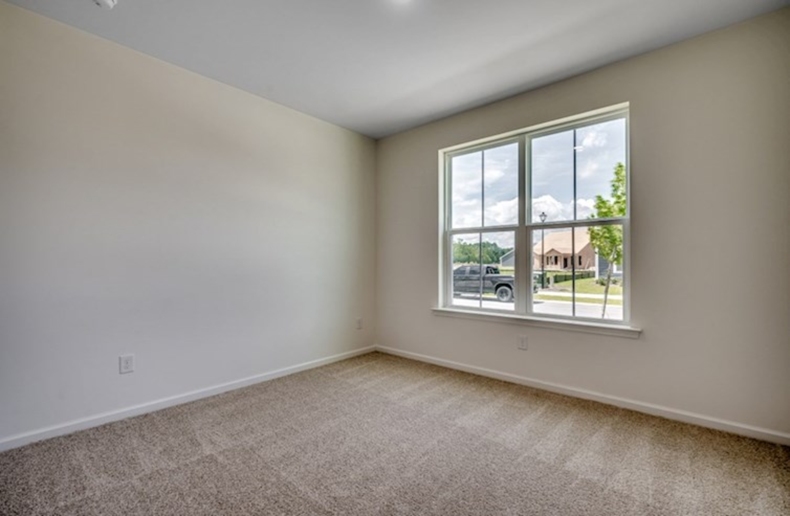 cozy room with tan walls, large window and carpeting throughout