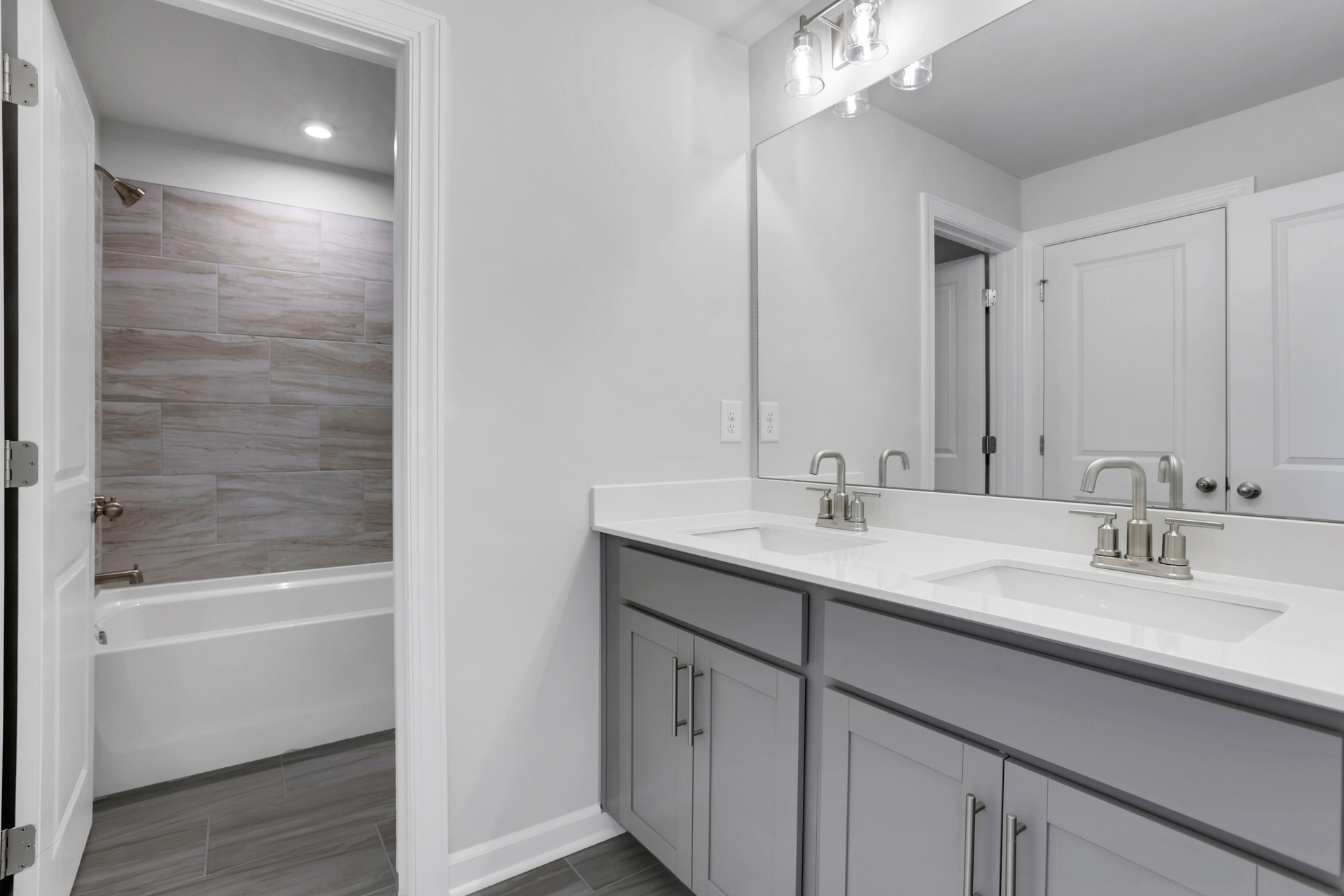 secondary bathroom with gray cabinets and white quartz counters