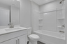secondary bathroom with white cabinets and quartz counters