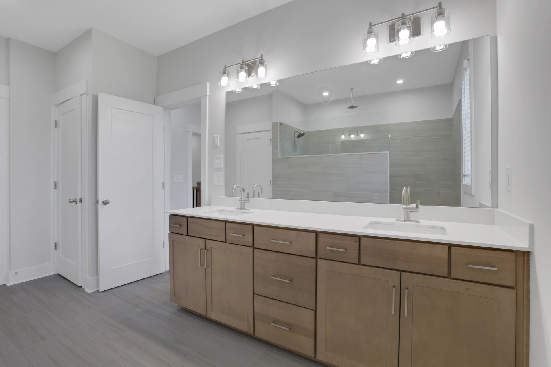 primary bathroom with wood-finish cabinets and white quartz counters