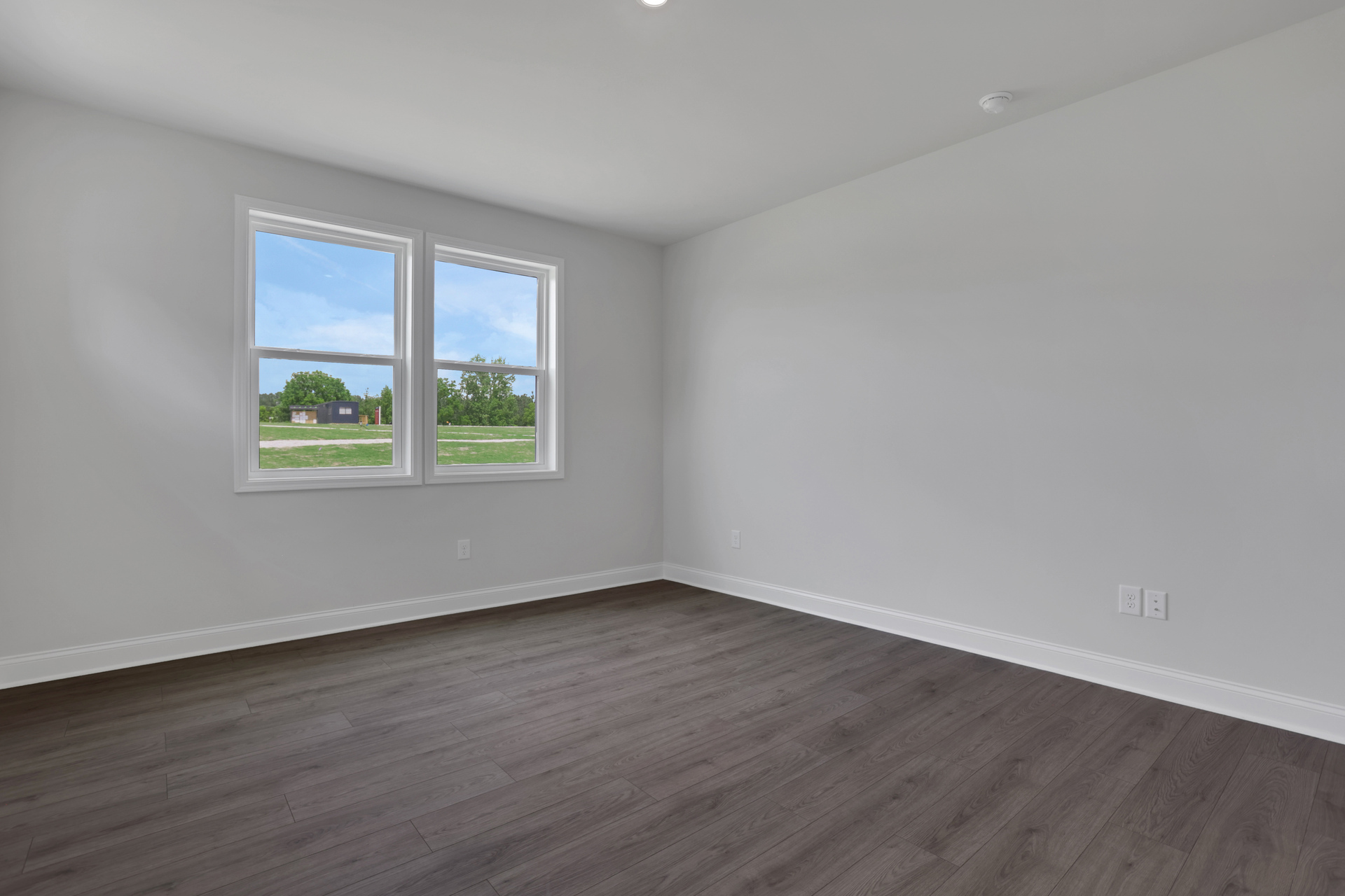 primary bedroom with windows and hard surface floors