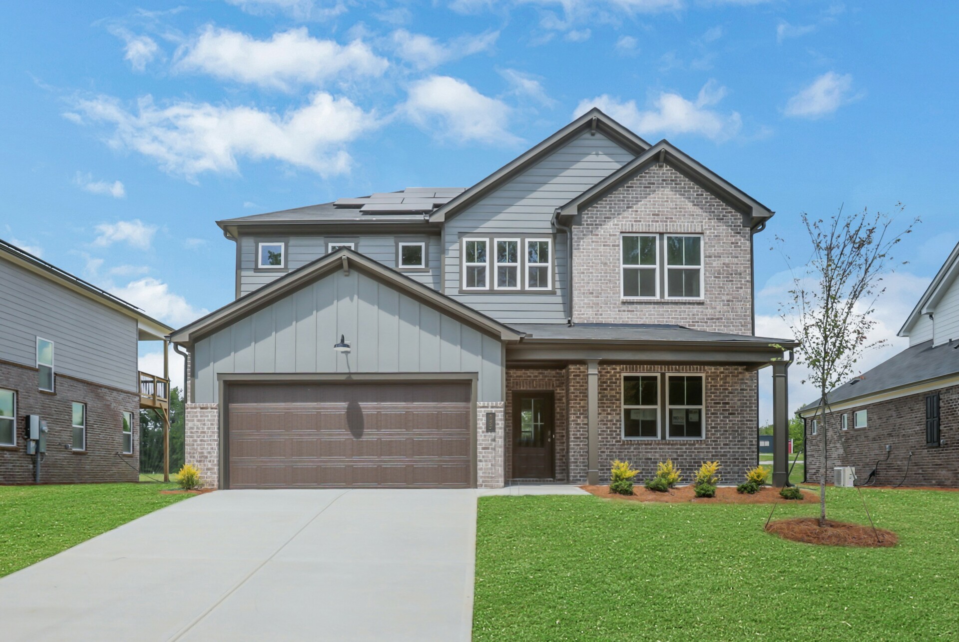 front of 2-story home with gray siding and brick detail