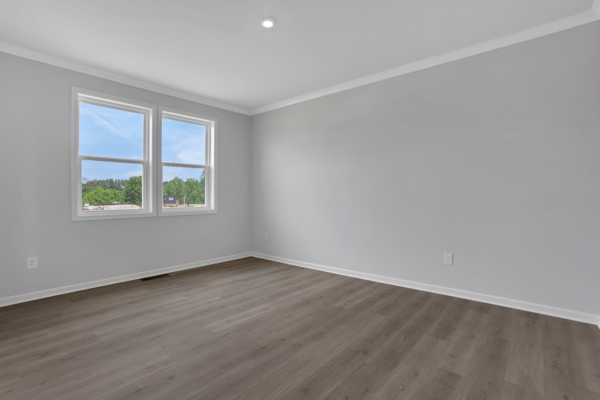 primary bedroom with hard-surface flooring and windows