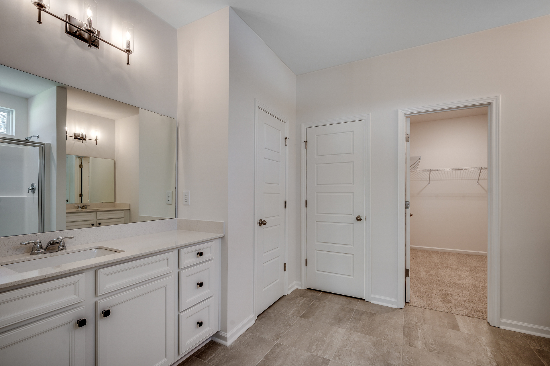 bright white cabinets with black hardware and tile flooring 