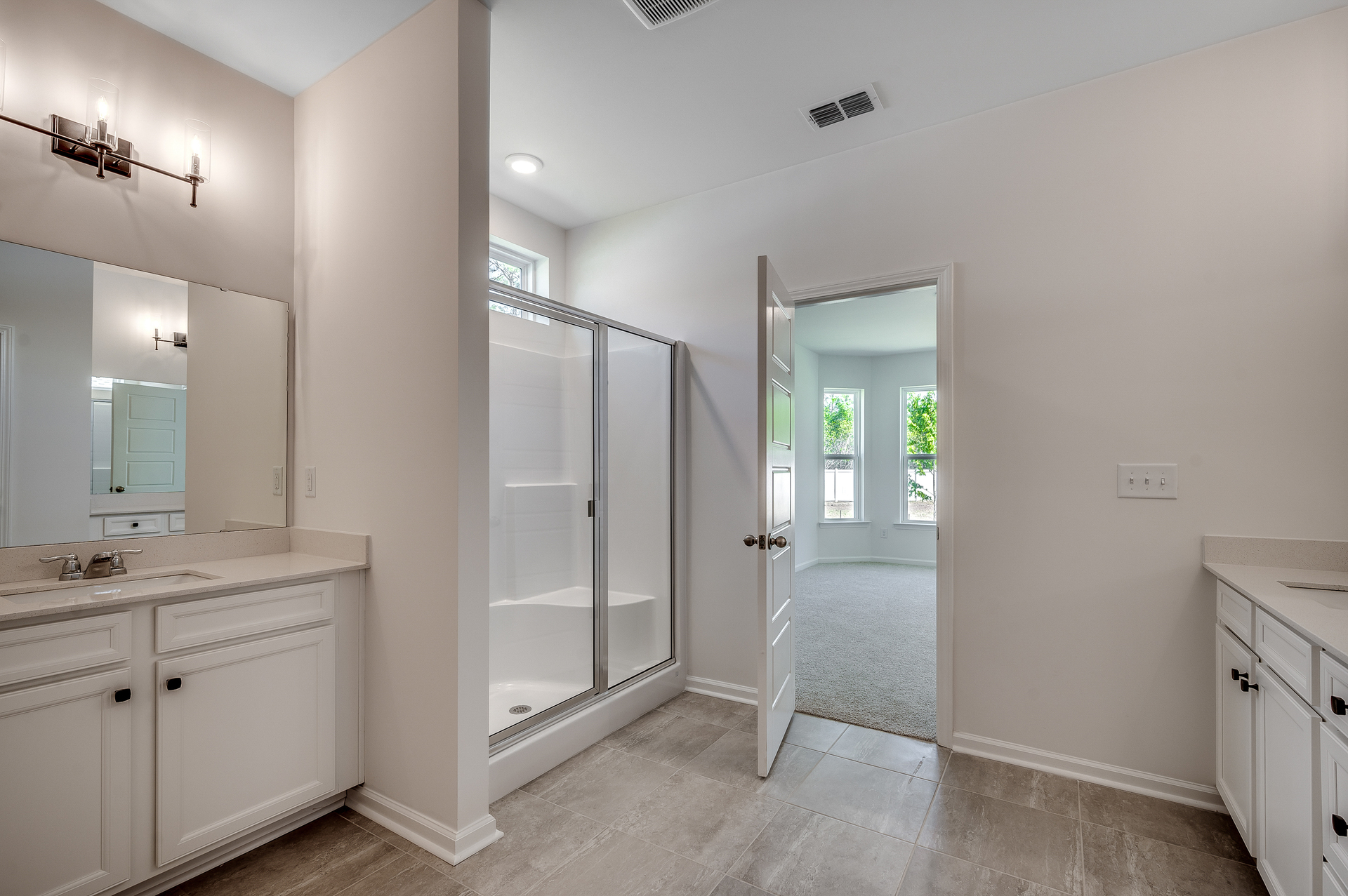 single sink vanity with bright white cabinets, large walk-in shower and tile flooring.