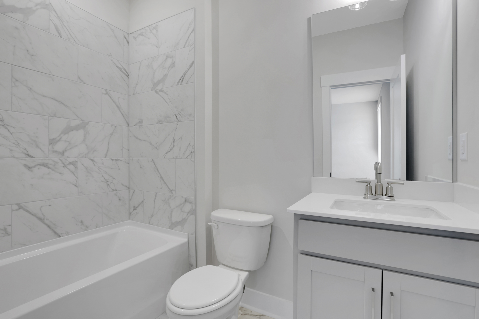 secondary bathroom with gray cabinets and white quartz counters