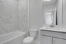 secondary bathroom with gray cabinets and white quartz counters