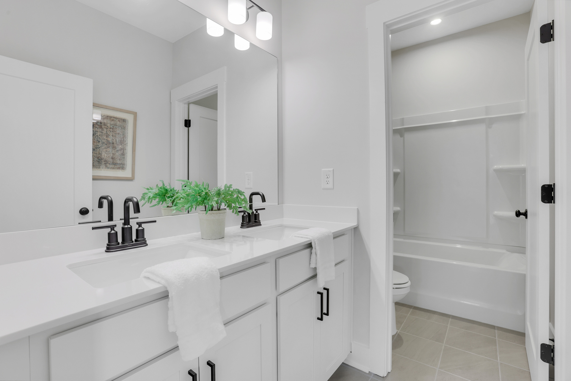 secondary bathroom with white cabinets and tile flooring