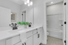 secondary bathroom with white cabinets and tile flooring