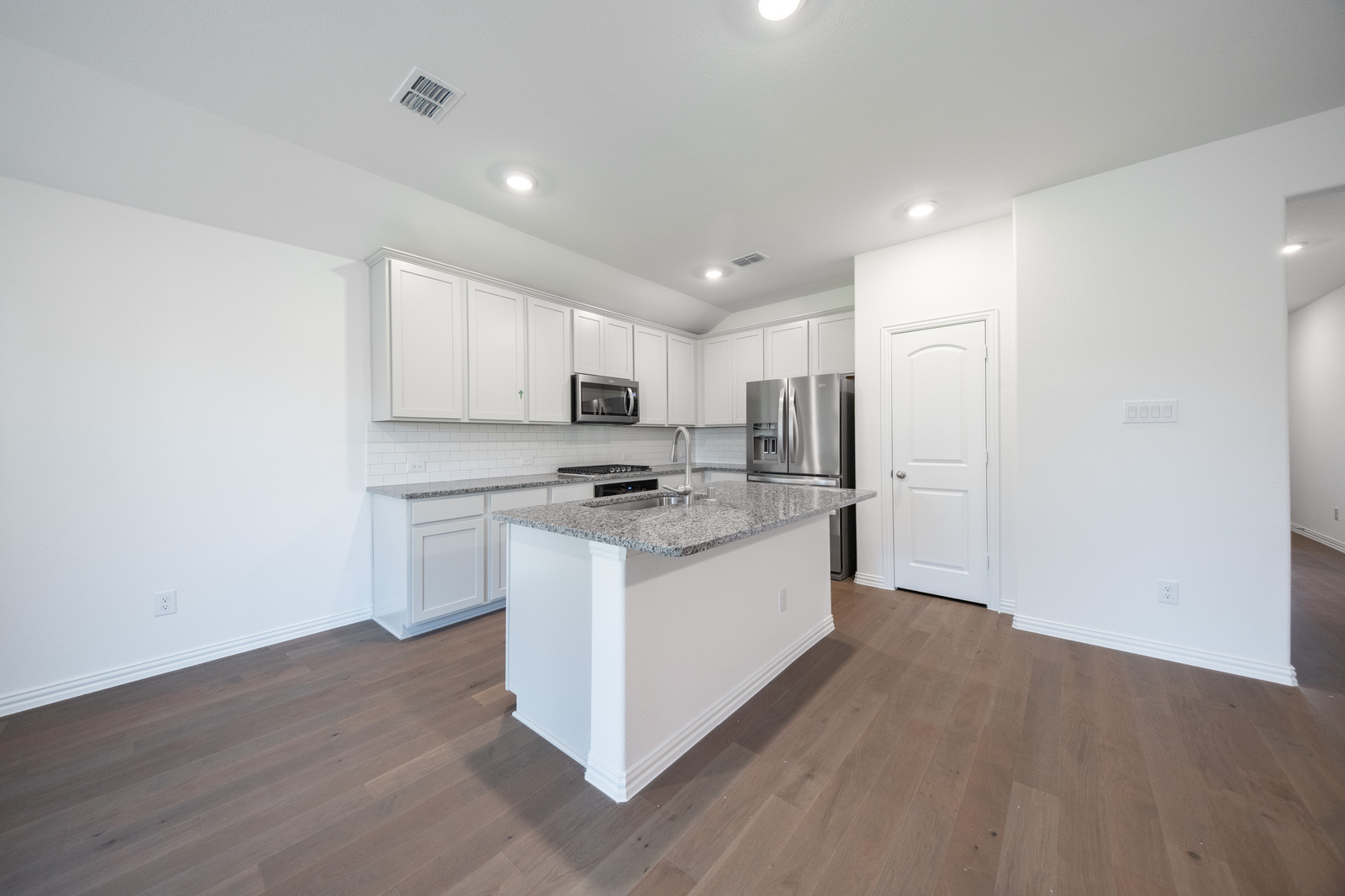 open kitchen with white cabinets and hardwood flooring