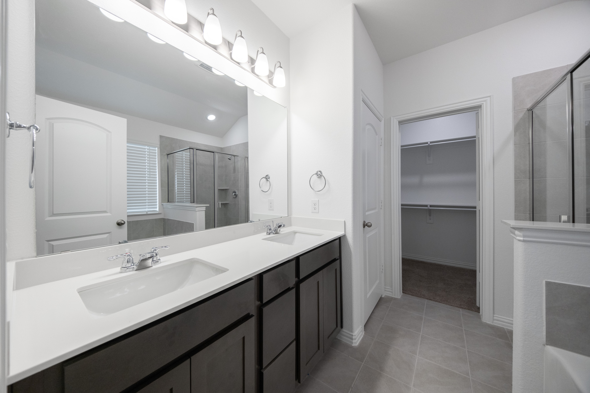 primary bathroom with double sinks and tile flooring