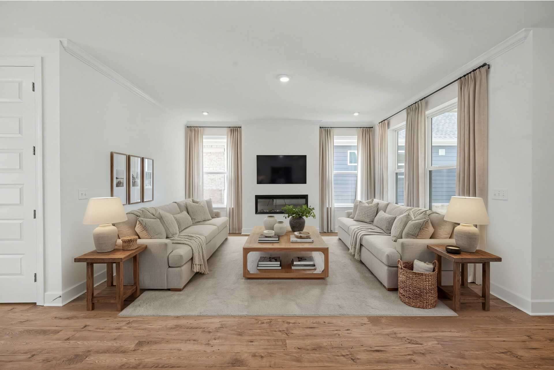 great room with wood flooring, sofas, coffee table, tv, fireplace, and large windows