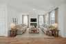 great room with wood flooring, sofas, coffee table, tv, fireplace, and large windows
